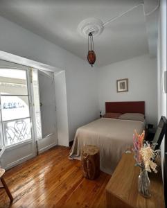 ein Schlafzimmer mit einem Bett und einem Tisch und einem Fenster in der Unterkunft La Casa de María Pita in A Coruña