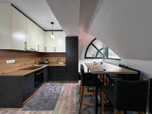 a kitchen with black and white cabinets and a table at Apartman Zen Fojnica in Fojnica