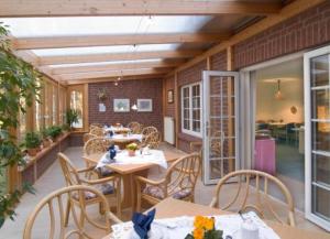 a dining room with tables and chairs and a patio at Hotel Ferien auf der Heid in Eversen