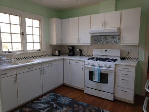 a kitchen with white cabinets and a stove top oven at Charming Classic Cottage 2Br in Durham