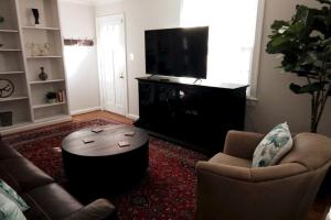 a living room with a tv and two chairs and a coffee table at Charming Classic Cottage 2Br in Durham