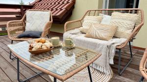a patio with a wicker couch and a glass table at Stylowe apartamenty in Charzykowy +17 photos