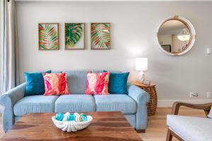 a living room with a blue couch with colorful pillows at Hip Hawaiian Oceanfront Vistas in Kihei +34 photos