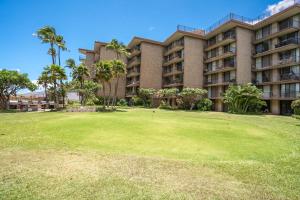 a large apartment building with a green yard at Hip Hawaiian Oceanfront Vistas in Kihei