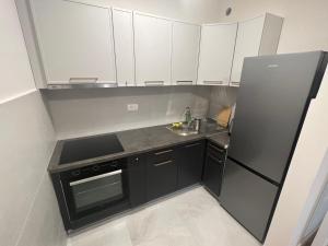 une cuisine avec des armoires blanches et un réfrigérateur noir dans l'établissement Luxapartment Montenegro, à Podgorica