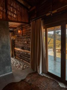 a room with a large window in a log cabin at Cabanas do Paiol Texas Cabin Toledo MG in Toledo