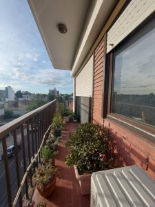 einen Balkon mit Topfpflanzen und einer Bank auf einem Gebäude in der Unterkunft Departamento ideal corta estadía in Ramos Mejía