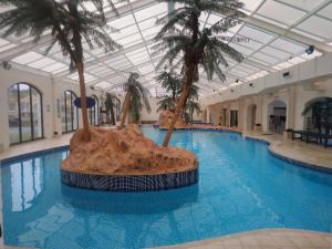 a large swimming pool with palm trees in a building at Dawlish Warren Welcome family holiday park South Devon Willow villa Welcome2Warren in Dawlish Warren