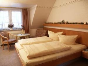 a bedroom with a large bed and a chair at Hotel Ferien auf der Heid in Eversen