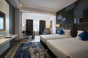 a hotel room with two beds and a desk at Best Western Plus Tejvivaan in Visakhapatnam