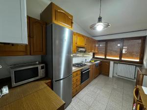 una cucina con frigorifero in acciaio inox e mobili in legno di La Dimora del Falconiere - Guest House a Sulmona