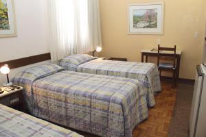 ein Hotelzimmer mit 2 Betten und einem Tisch in der Unterkunft Hotel São Bento in Belo Horizonte