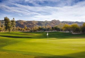 a green golf course with mountains in the background at The Legacy Golf Resort in Phoenix