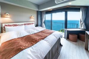 a bedroom with a bed with a view of the ocean at Nagasaki Chapel Coconuts Hotel ＆Resort in Isahaya
