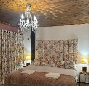 a bedroom with a bed with a chandelier at Campos do Jordão Chalés in Campos do Jordão +3 photos