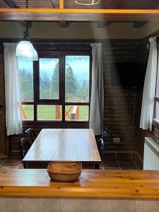 a wooden table in a room with two windows at La Margarita in El Bolsón
