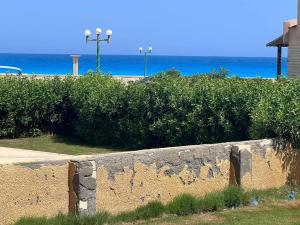 a stone wall next to a beach with the ocean at قرية دعاء السماء in El Hamam +2 photos