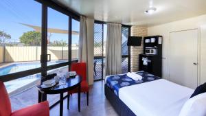 a hotel room with a bed and a table and a pool at Tropical Gateway Motor Inn in Rockhampton