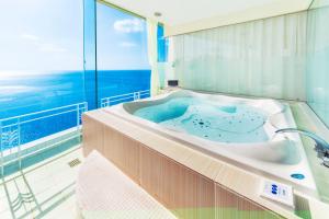 a bath tub in a room with a view of the ocean at Nagasaki Chapel Coconuts Hotel ＆Resort in Isahaya