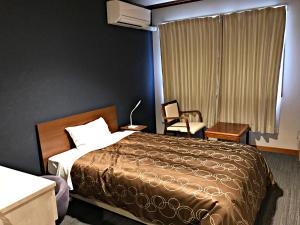 a hotel room with a bed and a chair at Yamamura Bekkan in Nagato