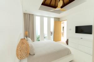 a white bedroom with a bed and a ceiling fan at Sonnys Uluwatu in Uluwatu