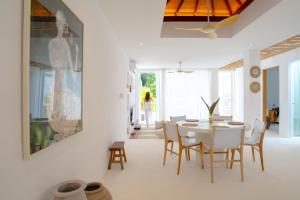 a dining room with a white table and chairs at Sonnys Uluwatu in Uluwatu
