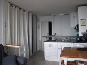 une cuisine avec des armoires blanches et une table en bois dans l'établissement Studio Cabine 4 Pers. - Exposé Plein Sud - FR-1-580-117, à Font-Romeu-Odeillo-Via