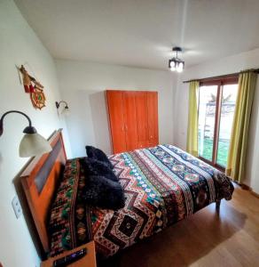 een slaapkamer met een bed met een kleurrijke deken erop bij Refugio en la ciudad in Pucón