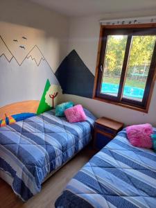 twee bedden in een kamer met bergen aan de muur bij Refugio en la ciudad in Pucón +27 foto's