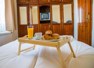 バンスコにあるPri Ani Guest Houseのベッドの上にパンとオレンジジュース1杯を用意したトレイ