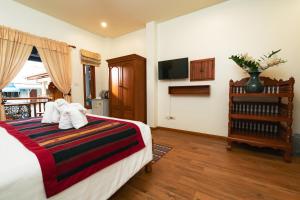 ein Schlafzimmer mit einem Bett mit Kissen und einem TV in der Unterkunft Gordnuea Boutique House in Chiang Mai