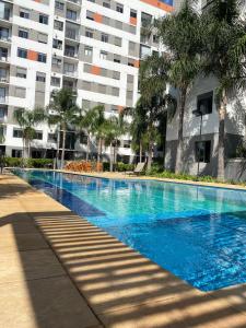 a blue swimming pool in front of a building at Apartamento confortável e com piscina em São Paulo in Sao Paulo