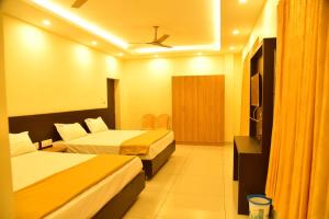 ein Hotelzimmer mit zwei Betten und einem Fernseher in der Unterkunft Hotel Devis Velankanni in Velankanni