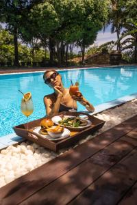 a man with a tray of food in a swimming pool at Villa SPACE in Unawatuna