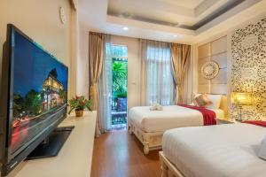 a hotel room with two beds and a flat screen tv at SHIN Hotel Chiangmai Gate in Chiang Mai