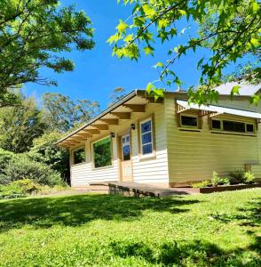 una piccola casa gialla con un prato di Riverwood Cottage, accessible accommodation a Warburton