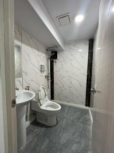 Un baño con un inodoro blanco y un lavabo. en Maine City Residences Tramo, en Manila