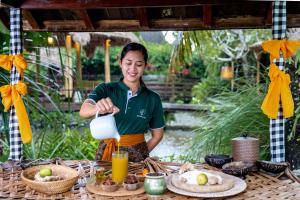 a man is pouring milk from a jug on a table at Arya Villas Ubud in Ubud +29 photos