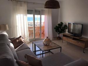 a living room with a couch and a tv at Mirando al Mar con Wifi y Terraza 1ª línea playa in Cádiz