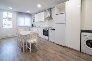a kitchen with white cabinets and a table and chairs at Sant Ferriol in Olot