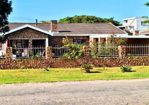 a brick fence in front of a house at Boknesstrand Self-catering Accommodation Holiday Home - a Mermaids Cottage minutes to the beach, lagoon, shops & more! in Boknes