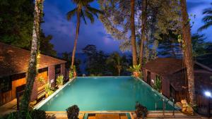a swimming pool in front of a house with palm trees at Baan Krating Khao Lak Resort - SHA plus in Khao Lak