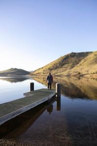 un homme marchant sur un quai à côté d'un plan d'eau dans l'établissement Merino Cottage Meadowbank Lake, à Ellendale