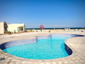a swimming pool with blue water in the middle at Sugardunes Beach Resort in Ghadw