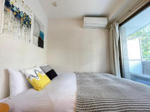 a bedroom with a bed with a yellow pillow and a window at シャンテ高田馬場22 in Tokyo