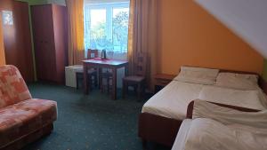 a hotel room with two beds and a table and a chair at JODA Pokoje Goscinne in Rewal
