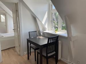 コペンハーゲンにあるCozy Apartment with Prime Location in Østerbroの窓のある部屋(黒いテーブル、椅子2脚付)