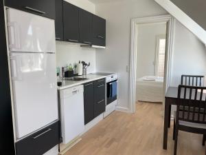 コペンハーゲンにあるCozy Apartment with Prime Location in Østerbroの黒いキャビネットと白い冷蔵庫のあるキッチン