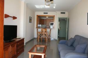 sala de estar con sofá azul y TV en Apartamentos Nerja Bahia en Nerja