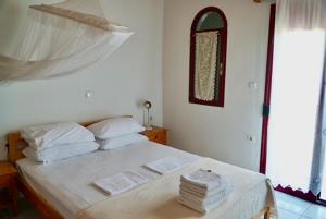 een slaapkamer met een bed met witte lakens en een raam bij Lefteris in Polichnítos